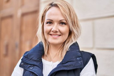 Sokakta kendine güvenen genç sarışın kadın gülümsüyor