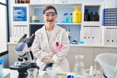Down sendromlu İspanyol kız bilim adamlarının laboratuarında çalışıyor gülümsüyor ve kahkahalar atıyor çünkü elleri vücutta komik bir şaka var.. 
