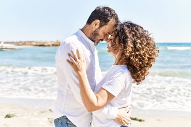 Orta yaşlı İspanyol çift sahilde sarılıyor..