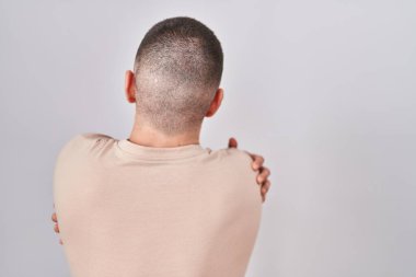 Young man standing over isolated background hugging oneself happy and positive from backwards. self love and self care 