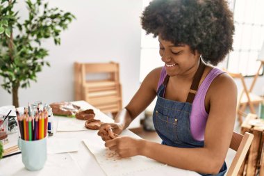 Genç afro-amerikan kadın gülümsüyor sanat stüdyosunda kil manipülasyonu yapıyor