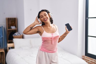 Genç, güzel İspanyol kadın yatak odasında müzik dinliyor ve dans ediyor.