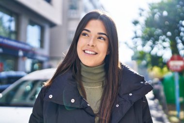 Young beautiful hispanic woman smiling confident looking to the side at street