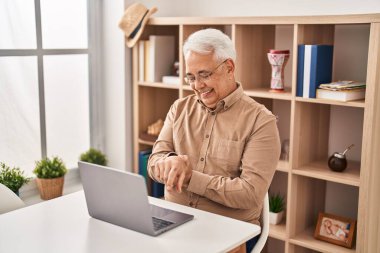 Senior man using laptop suffering for wrist pain at home