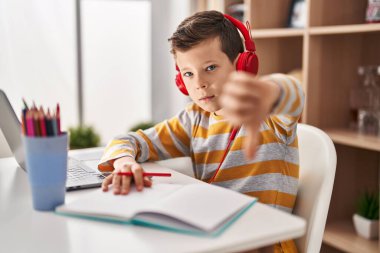 Genç, beyaz bir çocuk evde ödevini yapıyor. Kızgın bir yüzü var. Negatif işaretler baş parmakları aşağıda, reddedilme konsepti ise... 