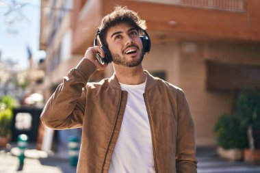 Sokakta müzik dinlerken kendinden emin gülümseyen İspanyol genç adam.