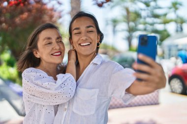 Two women mother and daughter make selfie by smartphone at park