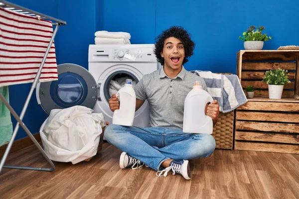 Hombre Hispano Con Pelo Rizado Lavando Ropa Sosteniendo Botellas Detergente — Foto de Stock