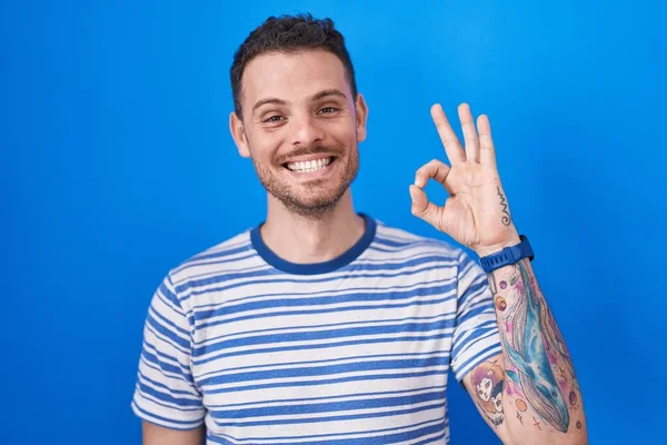 Mladý Hispánec Stojící Nad Modrým Pozadím Usmívající Pozitivně Dělá Pořádku — Stock fotografie
