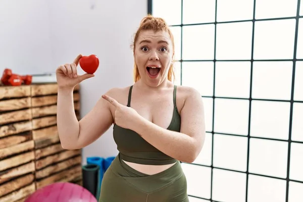 Ung Rödhårig Kvinna Håller Hjärtat Gymmet Ler Glad Pekar Med — Stockfoto