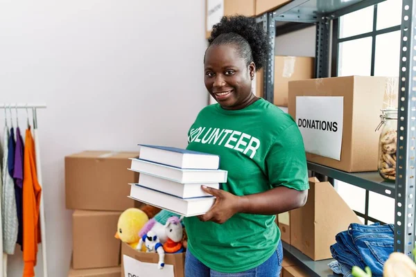 身穿志愿制服的年轻非洲裔美国妇女在慈善中心藏书 — 图库照片