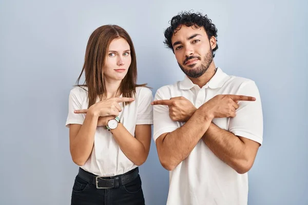 Pareja Joven Con Ropa Casual Pie Juntos Señalando Ambos Lados —  Fotos de Stock