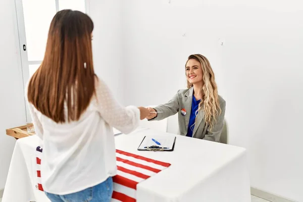 Young american voter woman giving party vote to electoral table worker.