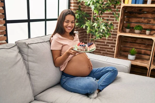 Young Latin Woman Pregnant Eating Sweets Sitting Sofa Home — Foto de Stock