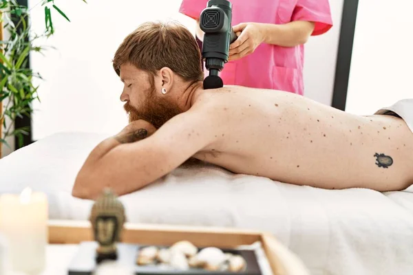 Young Redhead Man Having Back Massage Using Percussion Pistol Beauty — Zdjęcie stockowe