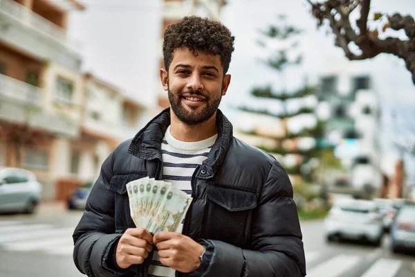 町の屋外でアラブ首長国連邦ディルハム紙幣を保持している若いアラブ人男性 — ストック写真
