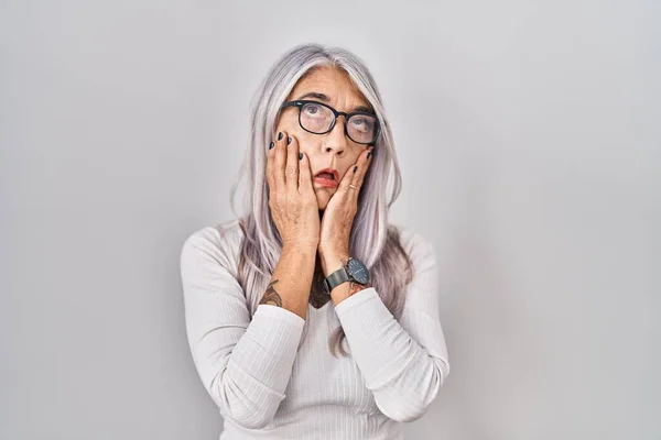 Middle age woman with grey hair standing over white background tired hands covering face, depression and sadness, upset and irritated for problem