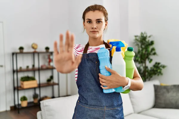 Jovem Morena Usando Avental Segurando Produtos Limpeza Com Mão Aberta — Fotografia de Stock