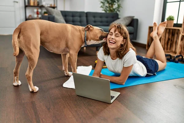 年轻的高加索女运动员微笑着 自信地用笔记本电脑和狗一起呆在家里 — 图库照片