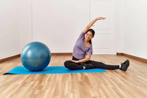 Mujer Latina Joven Sonriendo Confiado Estiramiento Usando Pelota Forma Centro —  Fotos de Stock