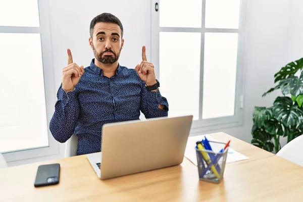 Jovem Hispânico Com Barba Trabalhando Escritório Com Laptop Apontando Para — Fotografia de Stock