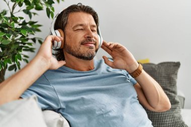 Middle age caucasian man smiling confident listening to music at home