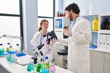 Erkek ve kadın bilim adamı partnerler VR gözlükleri tutuyor ve laboratuvarda kahve içiyorlar.