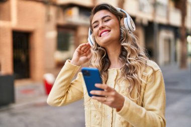 Sokakta müzik dinlerken kendinden emin gülümseyen genç bir kadın.