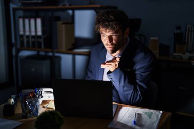 Geceleri ofiste çalışan Latin asıllı genç bir adam kameraya bakıp havada bir öpücük savuruyor ve sevimli ve seksi oluyor. aşk ifadesi. 