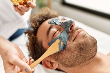 Genç İspanyol adam güzellik merkezinde yüz maskesi tedavisi görüyor.