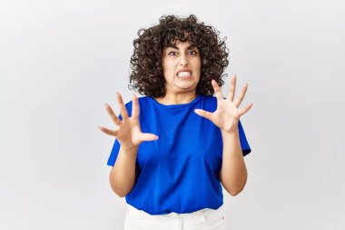 Ortadoğulu genç bir kadın, izole bir geçmişin başında korku ve korku ifadesinden korkarak ayakta duruyor. El hareketlerini durdur, şok içinde bağır. panik konsepti. 