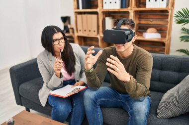 Kadın ve erkek klinikte sanal gerçeklik psikolojisi seansı yapıyorlar.