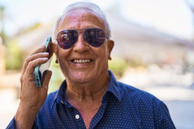 Senior grey-haired man smiling confident talking on the smartphone at street