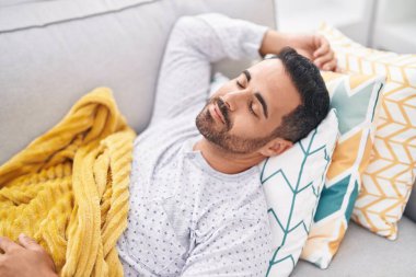 Genç İspanyol adam kanepede uzanıp evde uyuyor.