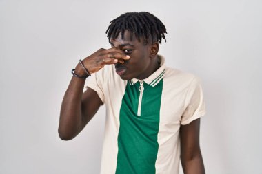 Münzevi arka planda duran Afrikalı bir adam pis ve iğrenç bir koku alıyor. Nefesini burnunda tutuyor. Kötü kokuyor. 