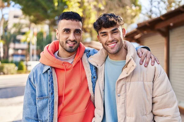 İki erkek caddede birbirlerine sarılıyorlar.