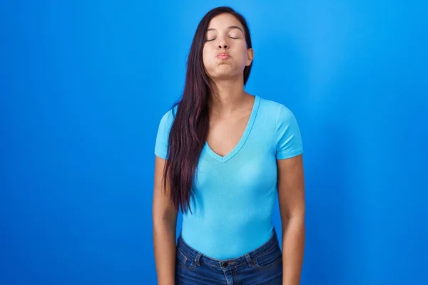 Tânără Hispanică Stând Fundal Albastru Umflând Obrajii Fața Amuzantă Gura — Fotografie, imagine de stoc