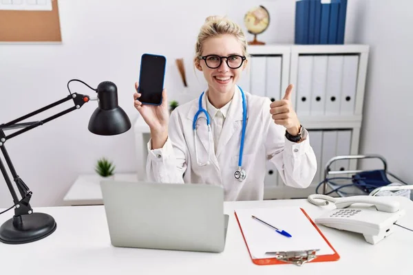 Joven Doctora Sosteniendo Teléfono Inteligente Mostrando Pantalla Blanco Sonriendo Feliz — Foto de Stock