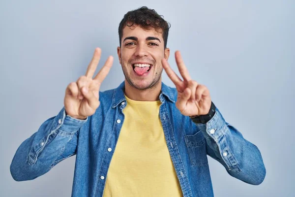 Joven Hombre Hispano Pie Sobre Fondo Azul Sonriendo Con Lengua — Foto de Stock