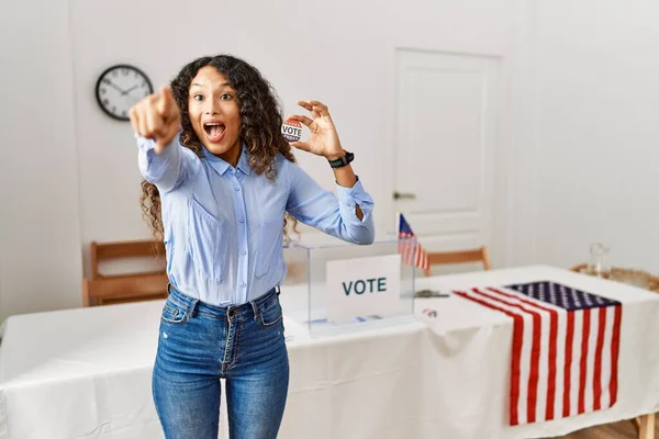 前に指を指して投票することによって政治運動に立っている美しいヒスパニック系の女性は 前方に何か 口を開けて驚きの表現 驚いて — ストック写真