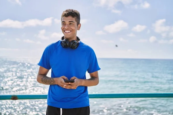 Joven Latino Sonriendo Feliz Usando Auriculares Smartphone Playa — Foto de Stock