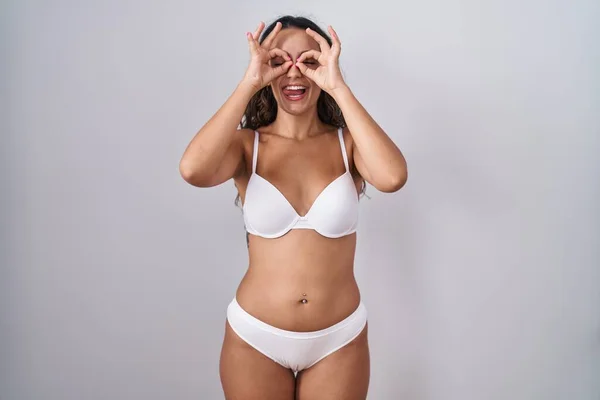Mulher Hispânica Jovem Vestindo Lingerie Branca Fazendo Gesto Como Binóculos — Fotografia de Stock
