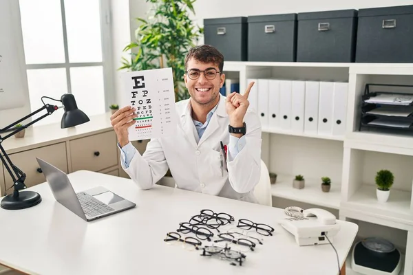 Jonge Spaanse Man Werkt Bij Oogheelkunde Kliniek Glimlachend Blij Wijzend — Stockfoto