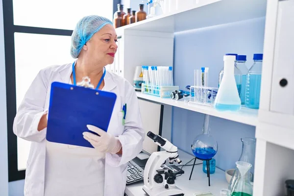 Middle Age Blonde Woman Wearing Scientist Uniform Writing Clipboard Laboratory — Zdjęcie stockowe