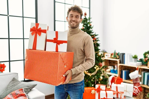 Jovem Hispânico Sorrindo Confiante Segurando Presentes Natal Casa — Fotografia de Stock