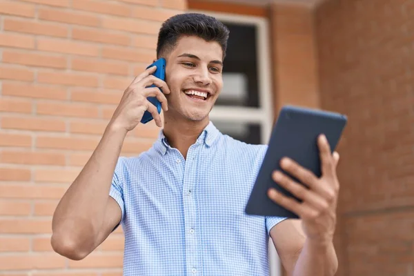 Young Hispanic Man Talking Smartphone Using Touchpad Street —  Fotos de Stock