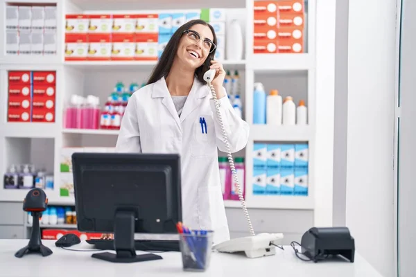 Young Beautiful Hispanic Woman Pharmacist Talking Telephone Using Computer Pharmacy — Zdjęcie stockowe