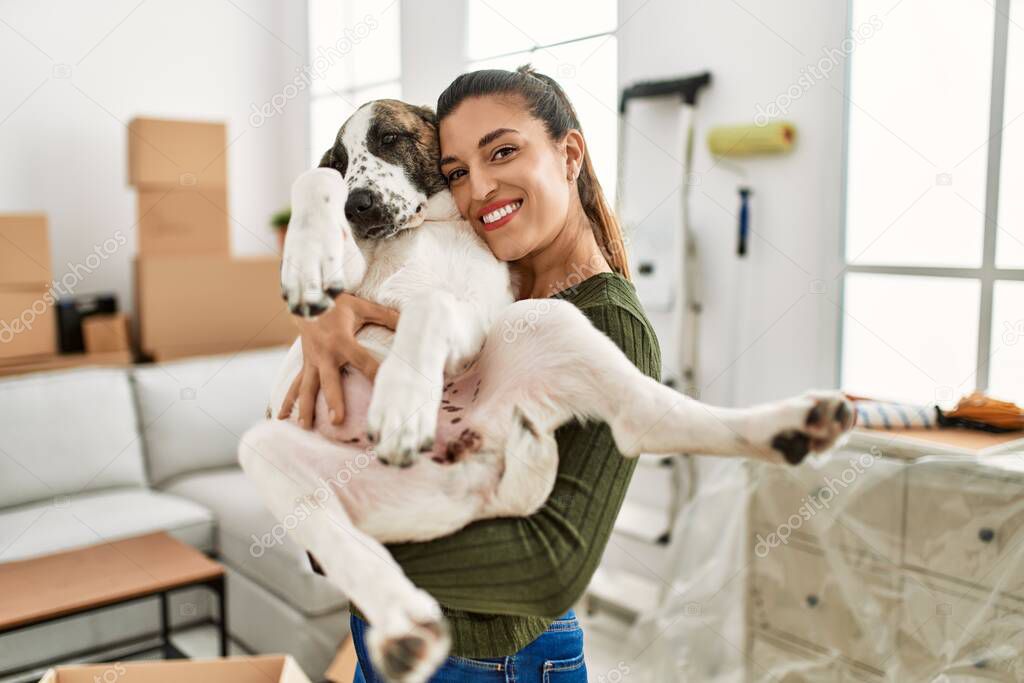 Young woman smiling confident hugging dog at home