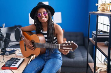 Müzik stüdyosunda klasik gitar çalan Afrikalı Amerikalı kadın müzisyen.