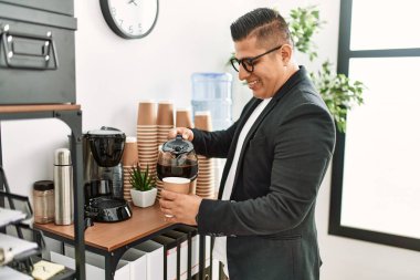 Genç Latin iş adamı gülümseyerek ofiste kahve içiyor..